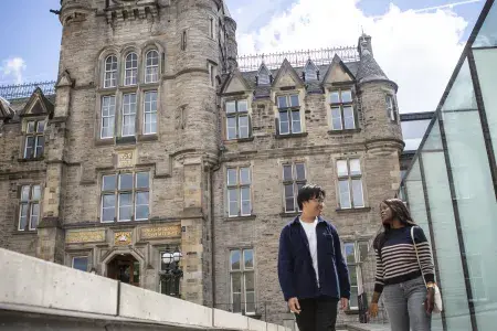 Two students in front of the Edinburgh Futures Institute building